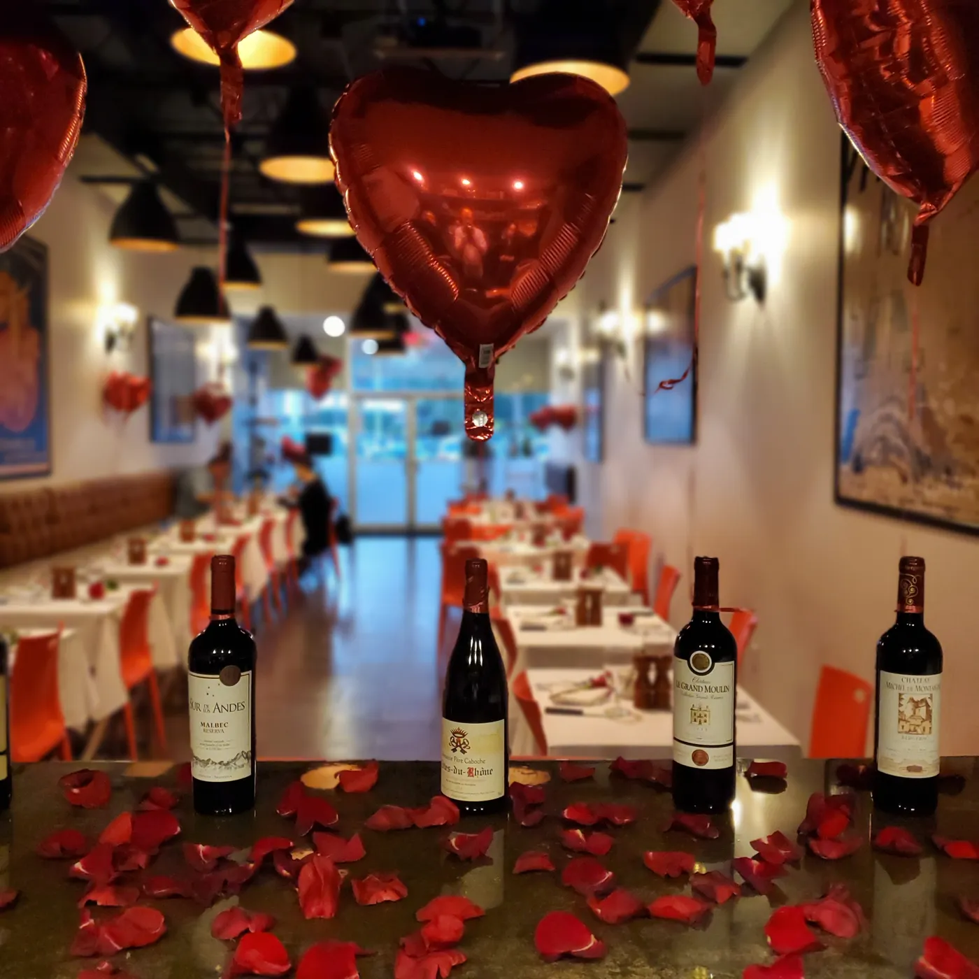 Evening at Lentrecote: red wines on the bar with rose petals and heart balloons